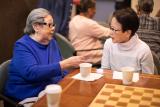 Two women sit at a table drinking coffee and talking at Simon C. Fireman Community in Randolph, MA