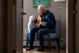 senior man sitting with dog playing guitar