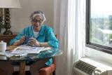 Older woman sitting at a table reading newspaper