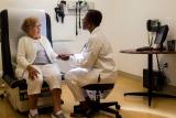 Older woman sitting in doctor office chair seeing a woman doctor