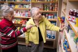 Two older women in a shop looking at items on shelves