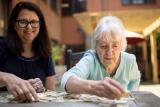 Older woman doing a puzzle with an adult woman