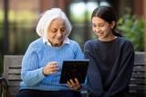 Older woman sitting with a young girl and holding a photo