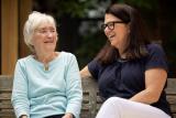 Older woman sitting on a bench with a younger woman.