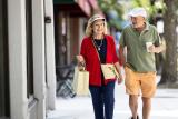 Older couple walking outside past stores
