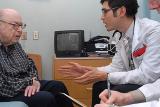 Older man sitting and talking with two doctors.