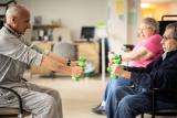 Physical therapist showing older adults exercises to do with dumbbells while sitting down