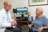 Male doctor sitting with an older woman discussing care