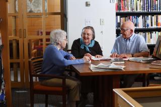 Group of senior citizens having a discussion in a library.