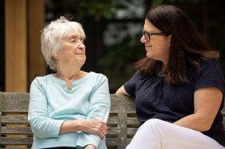 Older woman sitting on a bench with another woman