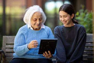 Older woman sitting with a young girl and holding a photo