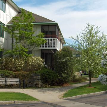 An external view of Orchard Cove with beautiful flowering plants lining a sidewalk.