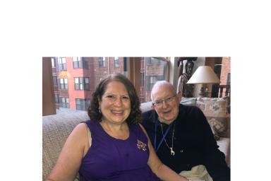 A daughter sits with her senior father in his NewBridge apartment.