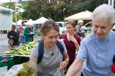 Two women pick out vegetables at a Farmer's Market