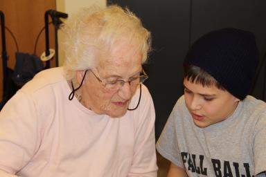 A resident and a child look down together at an IPad