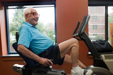 Male resident smiles while working out on a stationary bicycle in a gym