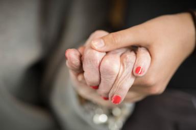 Two people hold hands - one of them is wearing red nail polish