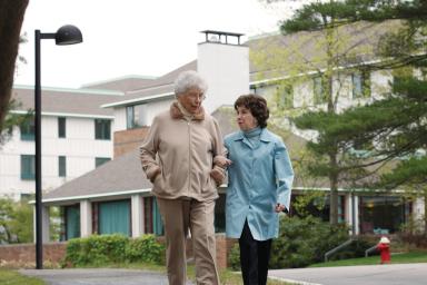 Two female friends walk together arm in arm 