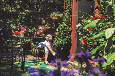 A female NewBridge resident sits in a garden with her dog.