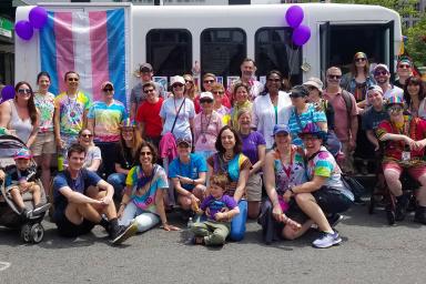 A group of HSL employees and residents stand in front of a bus at the Boston Pride Parade