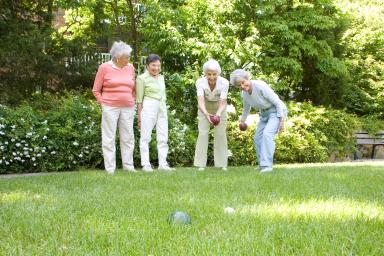 Four female residents play bocce ball outside 
