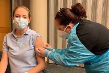 A HSL employee smiles while she receives a flu shot.