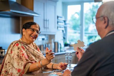 Older couple sitting in kitchen putting together a puzzle.