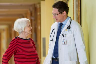 Doctor walking with older woman in a hallway