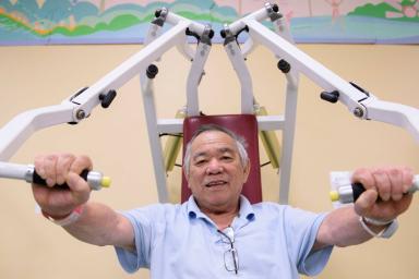 Older man using weight training machine