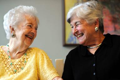 Two older women sitting together smiling.