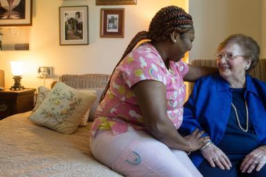 Nurse sitting with older woman in LTC