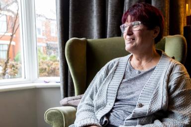 Older woman sitting in a chair looking outside