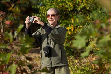 Older woman smiling taking a photo in nature