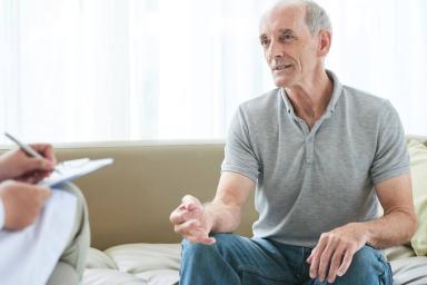 Older man sitting down with a doctor talking.