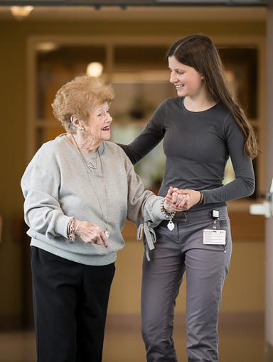 A staff person and a patient walking down a hallway.