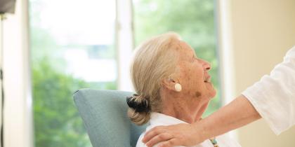 A female resident looks up and smiles as someone pats her shoulder