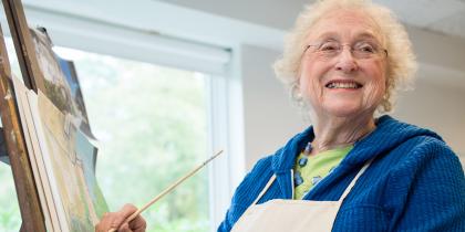A resident smiles while working on an art piece