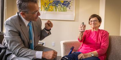 Doctor in grey suite with patient using a medical device.