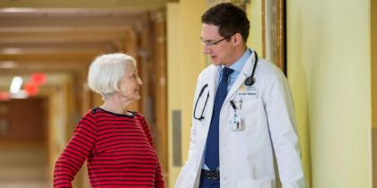 Doctor walking with older woman in a hallway
