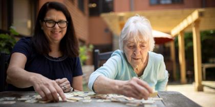 Older woman doing a puzzle with an adult woman