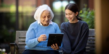 Older woman sitting with a young girl and holding a photo