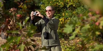 Older woman smiling taking a photo in nature