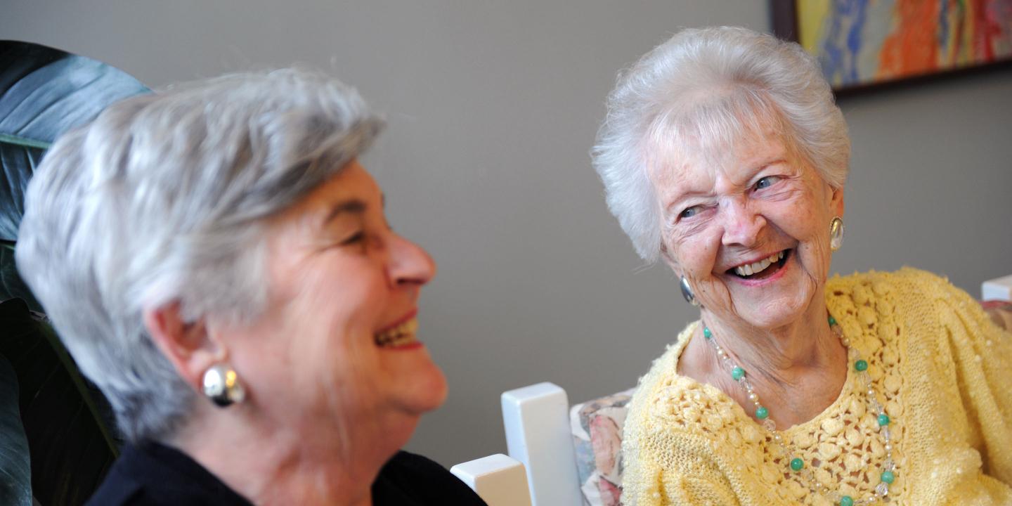 Adult daughter laughs with her mother, a long-term chronic care patient at Hebrew Rehabilitation Center