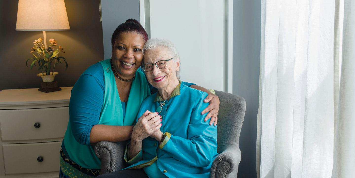 A memory care assisted living resident spends time with a beloved team member in her apartment at NewBridge on the Charles.