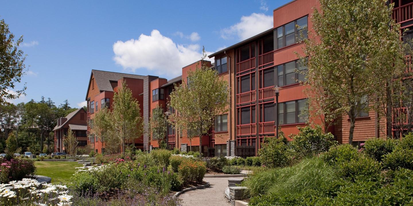 An exterior view of NewBridge on the Charles independent living apartment buildings, which connect to the community center and overlook a large garden courtyard.