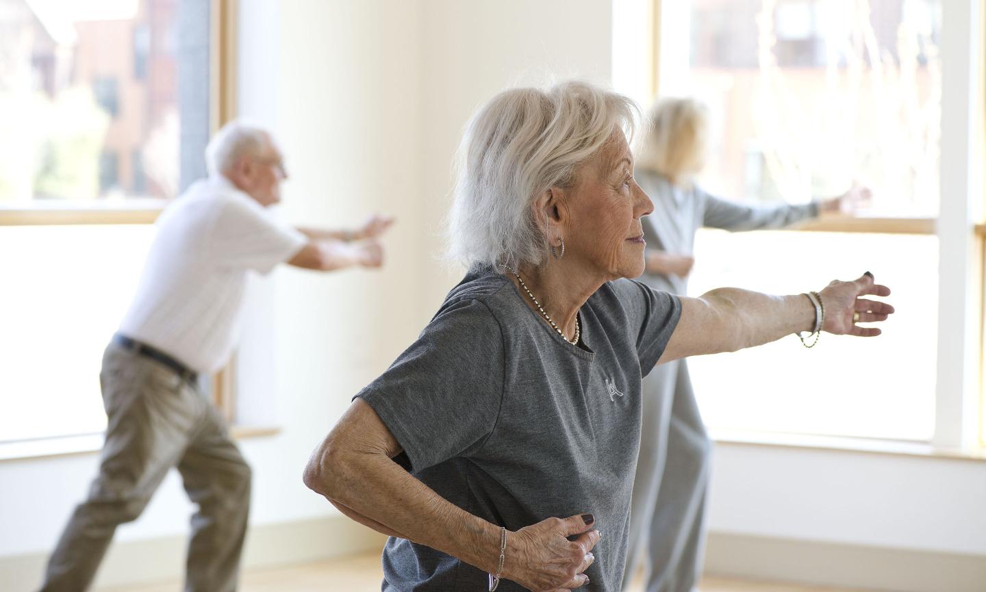 Two women and a man practice tai chi in a class at NewBridge on the Charles