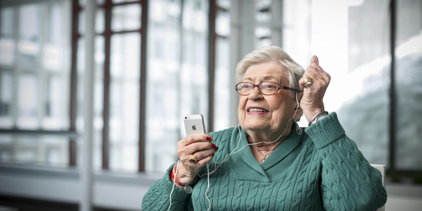 Older woman listens to music on an iPod.