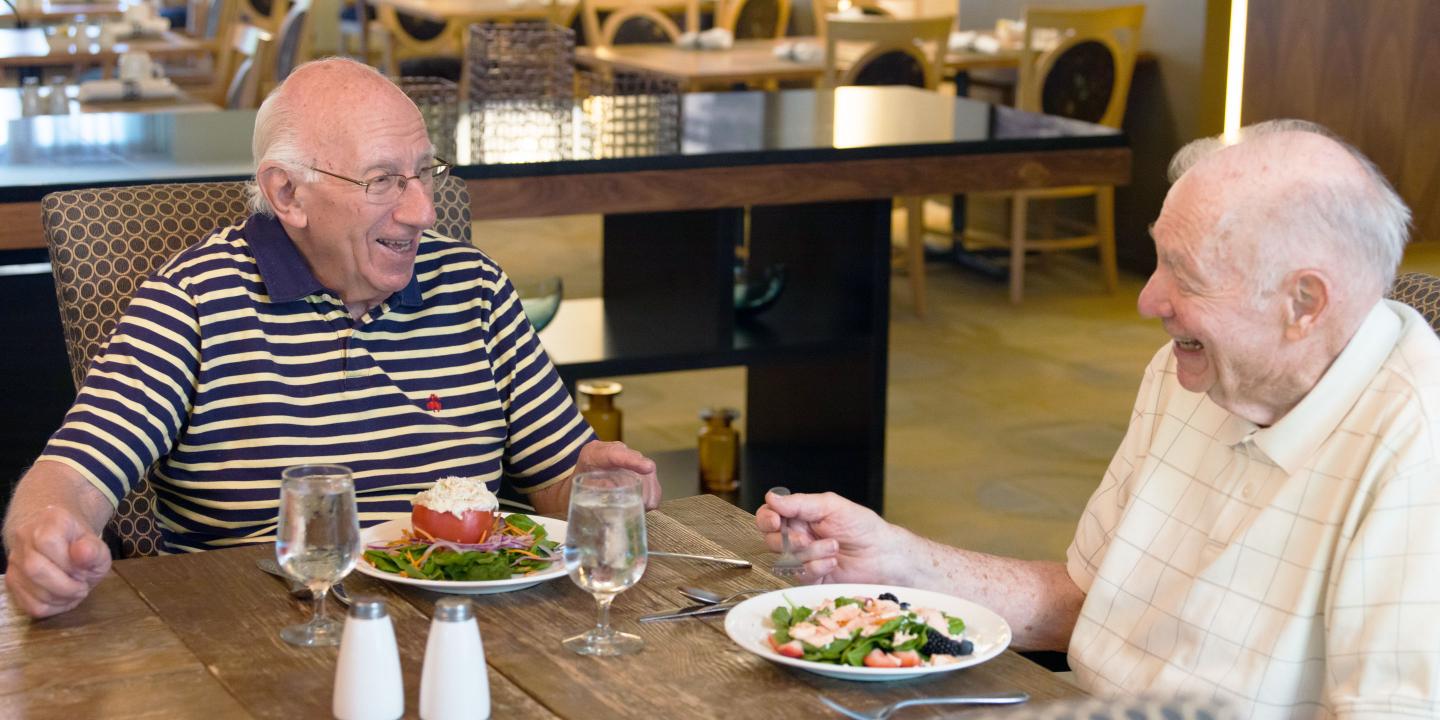 Two friends laugh over a meal in the Orchard Cove Pequit restaurant.