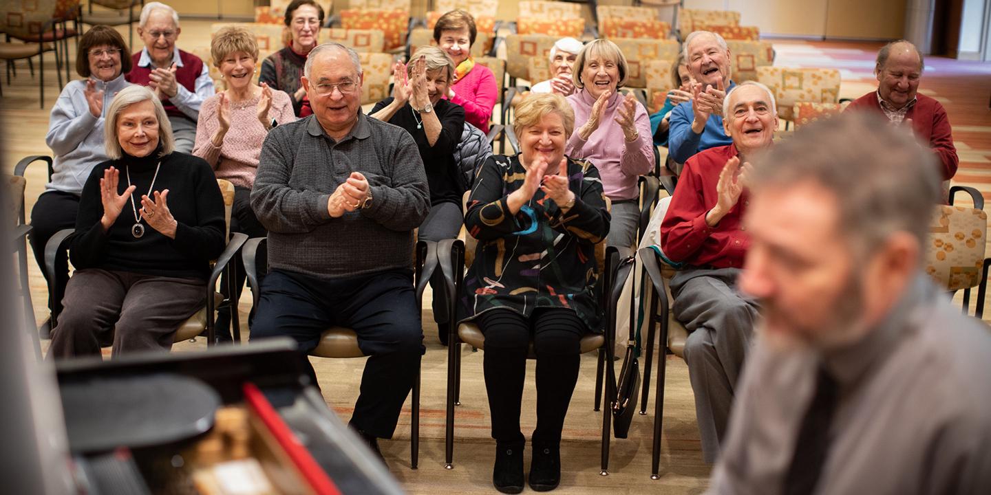 A crowd of seniors enjoy a live performance in Great Meadow Hall.