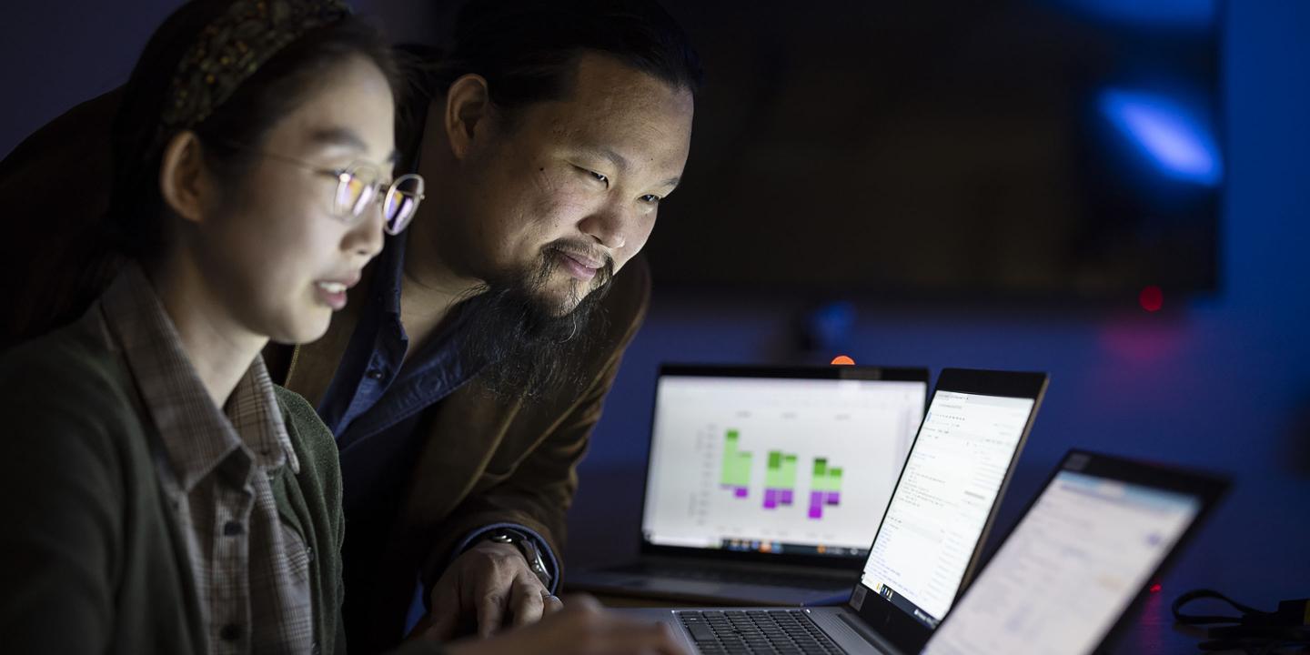 Two researchers review data on computer screens.